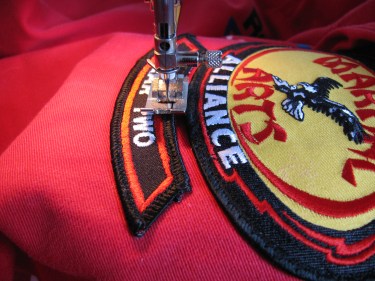 sewing on a patch on a karate uniform, 217