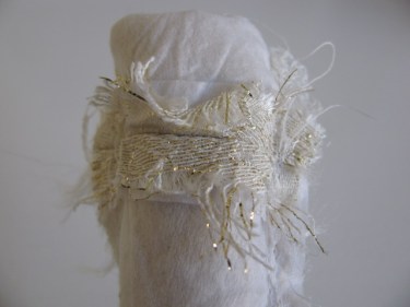view of the wide strap turned inside out with frayed edges, white brocade