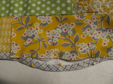 The new piece is pinned in place near the bottom edge of the quilt